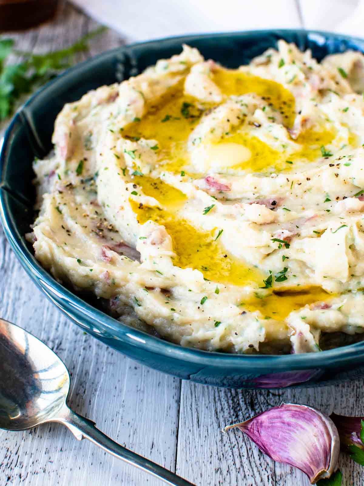 Mashed potatoes with red skin in a blue bowl with melted butter on top.