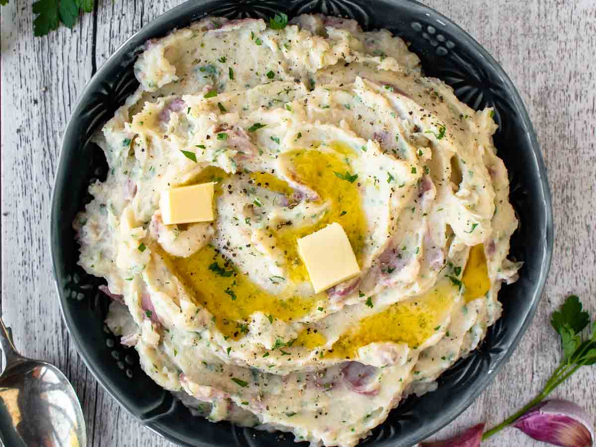 Overhead view of mashed potatoes in a blue bowl with butter melting on top.