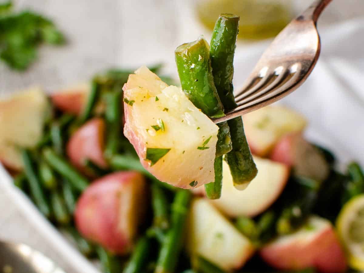 Close up of green beans and potatoes on a fork.