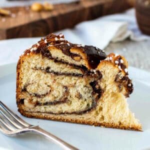 Wedge of nutella bread with swirls of chocolate inside on a white plate.