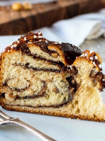 Wedge of nutella bread with swirls of chocolate inside on a white plate.