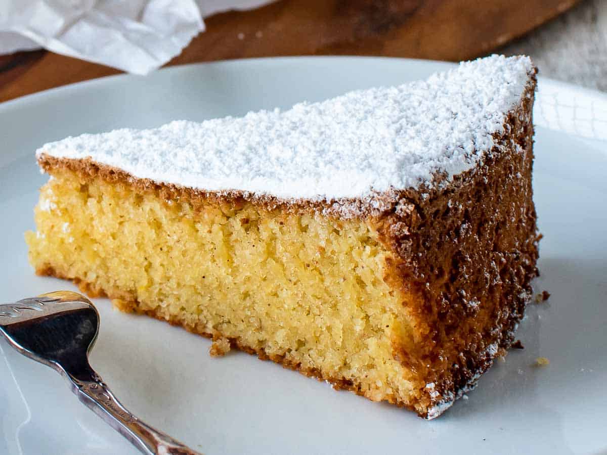 Close up of a slice of yellow cake on a white plate.