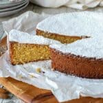 Spanish almond cake on a wooden board with a slice cut and slightly pulled out.