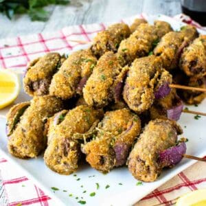 Spiedini on wooden skewered piled onto a white plate.