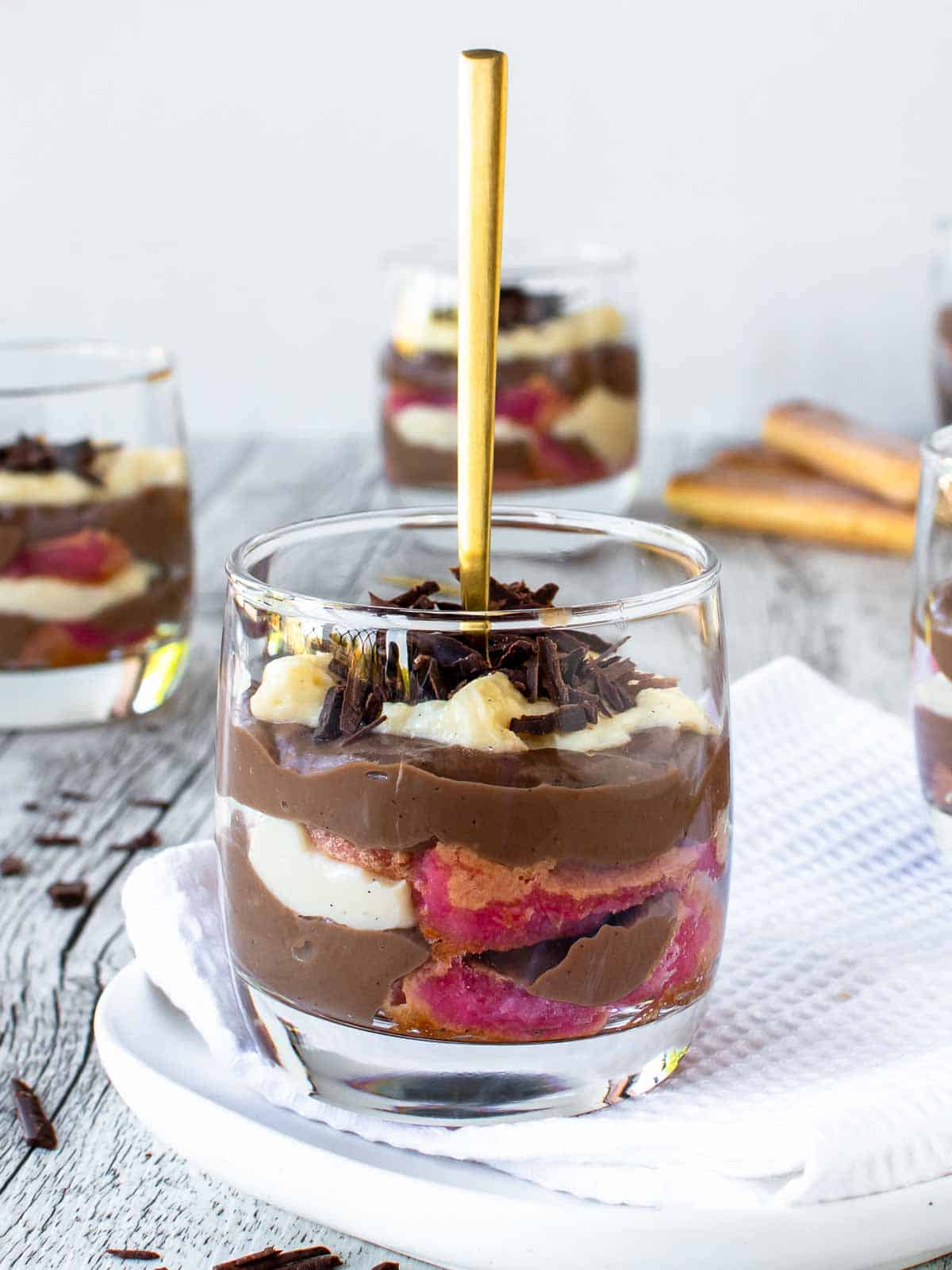 Zuppa Inglese in a glass with a gold spoon standing upright in the dessert.