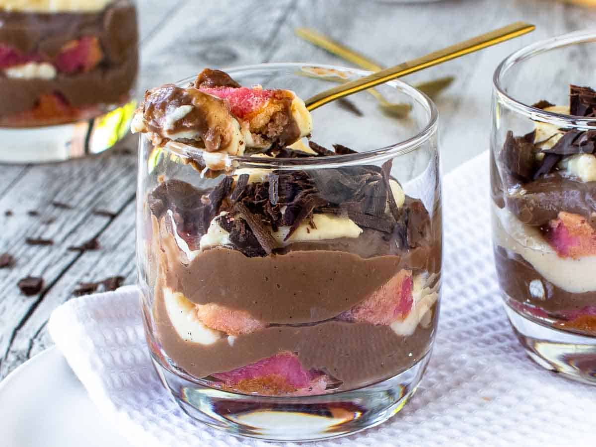 Layered dessert in a glasses with a spoonful being taken.