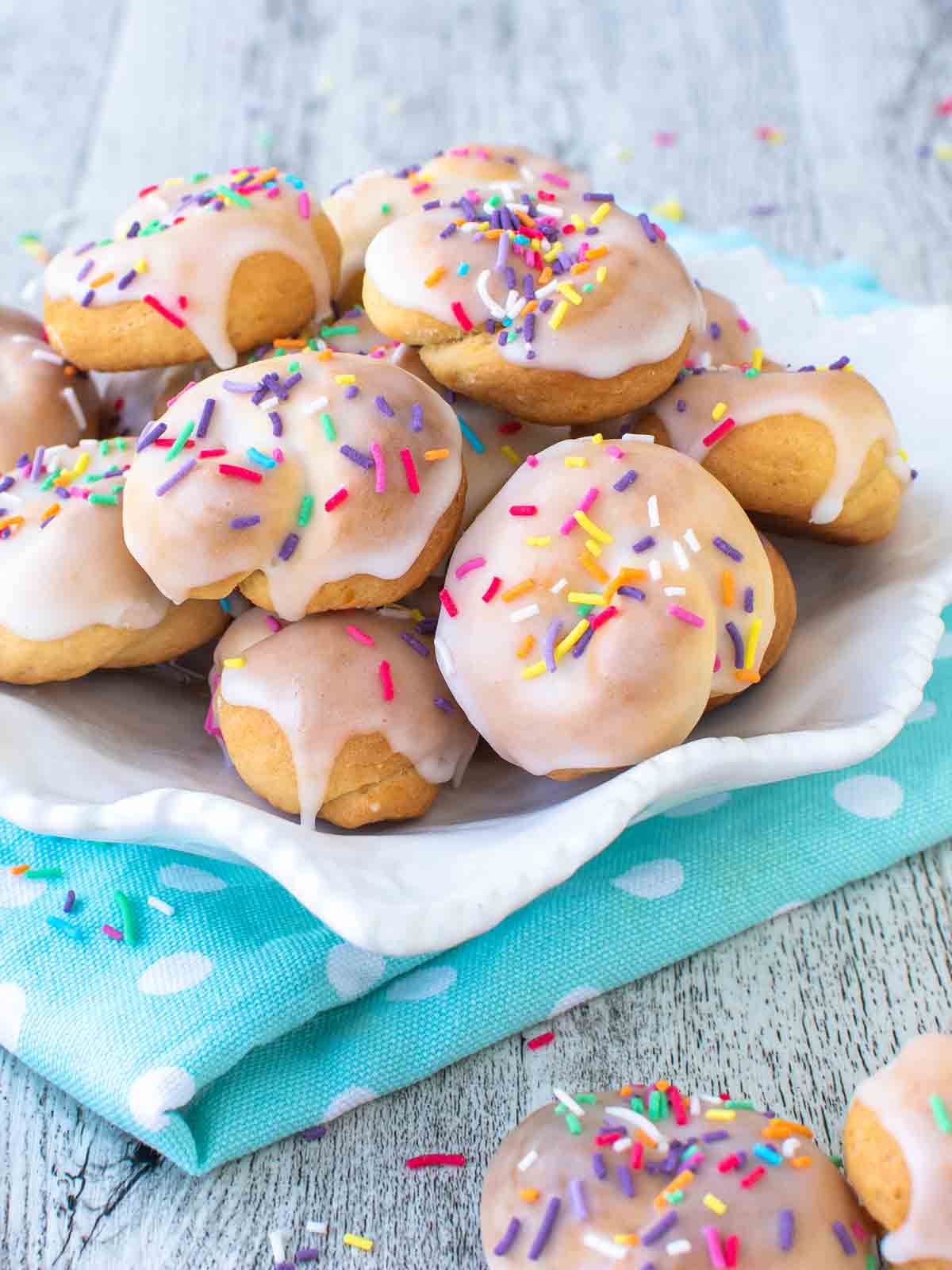 Italian knot cookies on a white plate on a sky blue cloth.