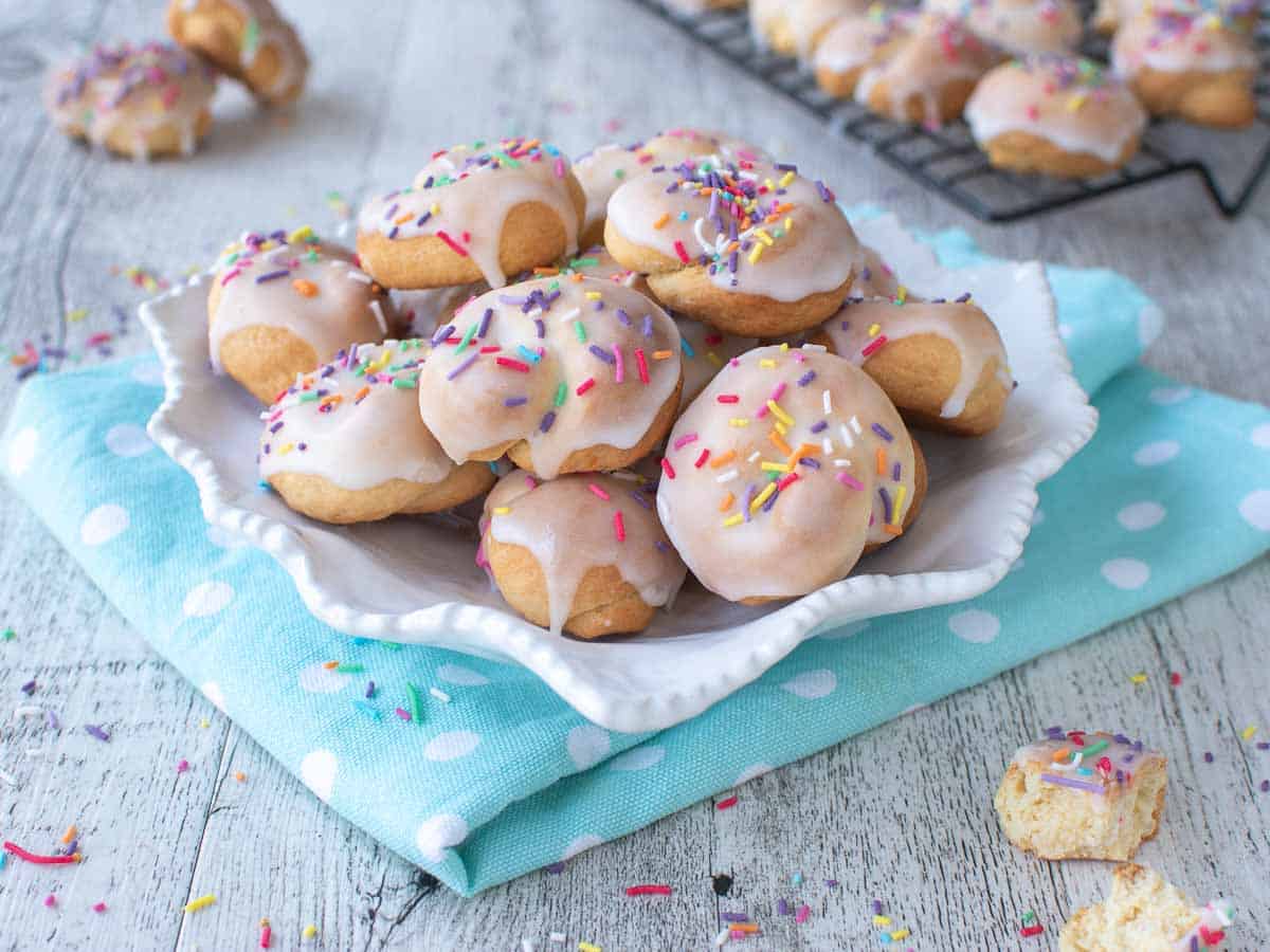 Italian love knot cookies on a white plate with sky blue cloth underneath.