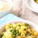 Pasta and peas in a white bowl on a sky blue napkin.