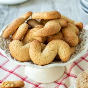 Italian S Cookies piled onto a small white cake stand.