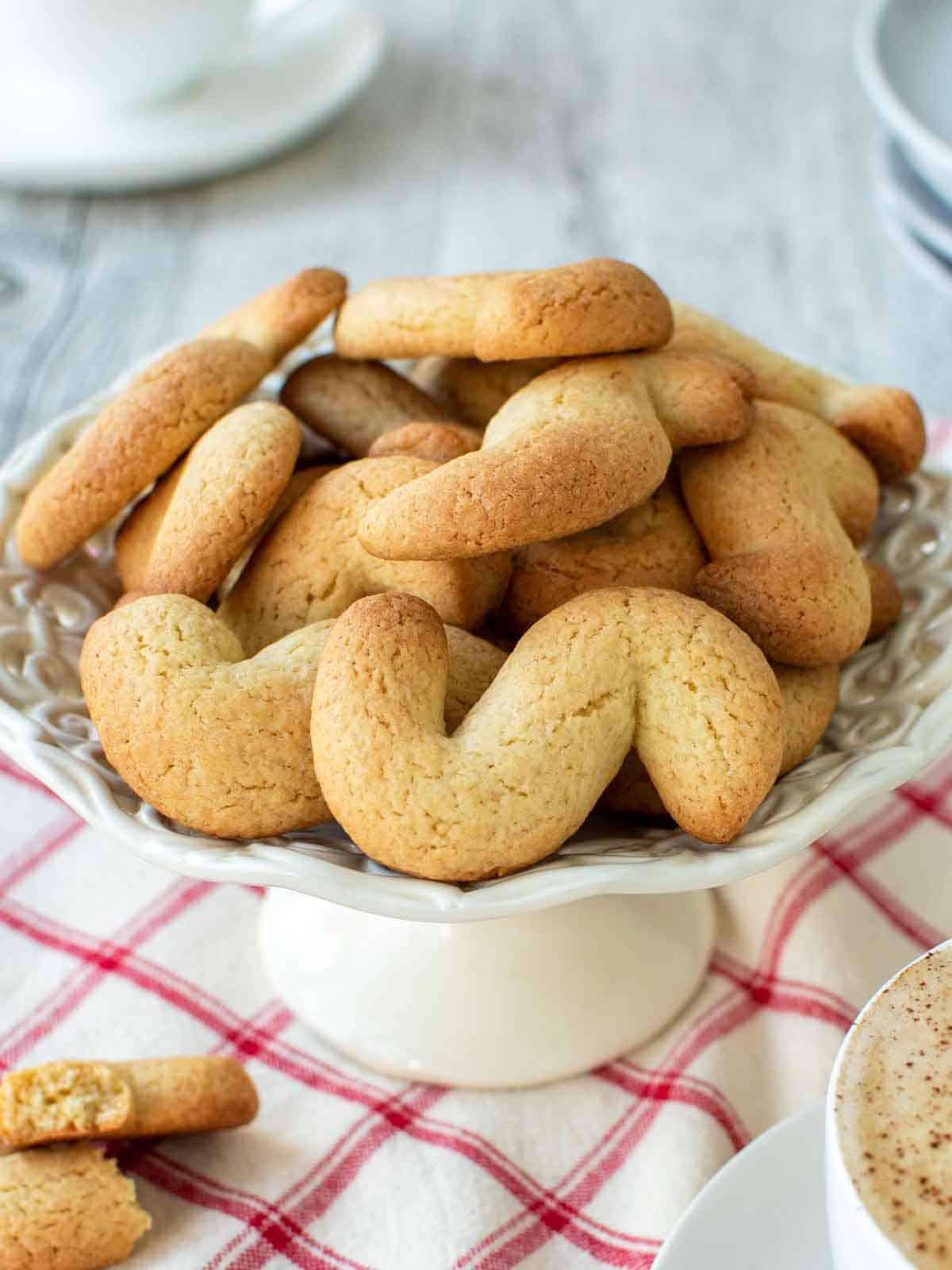 Italian S Cookies piled onto a small white cake stand.