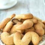 Italian S Cookies piled onto a small white cake stand.