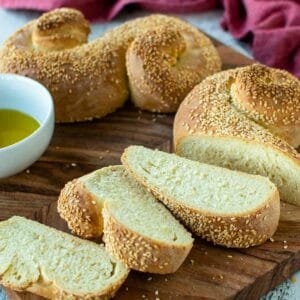 Semolina bread with three slices cut all on wooden board.