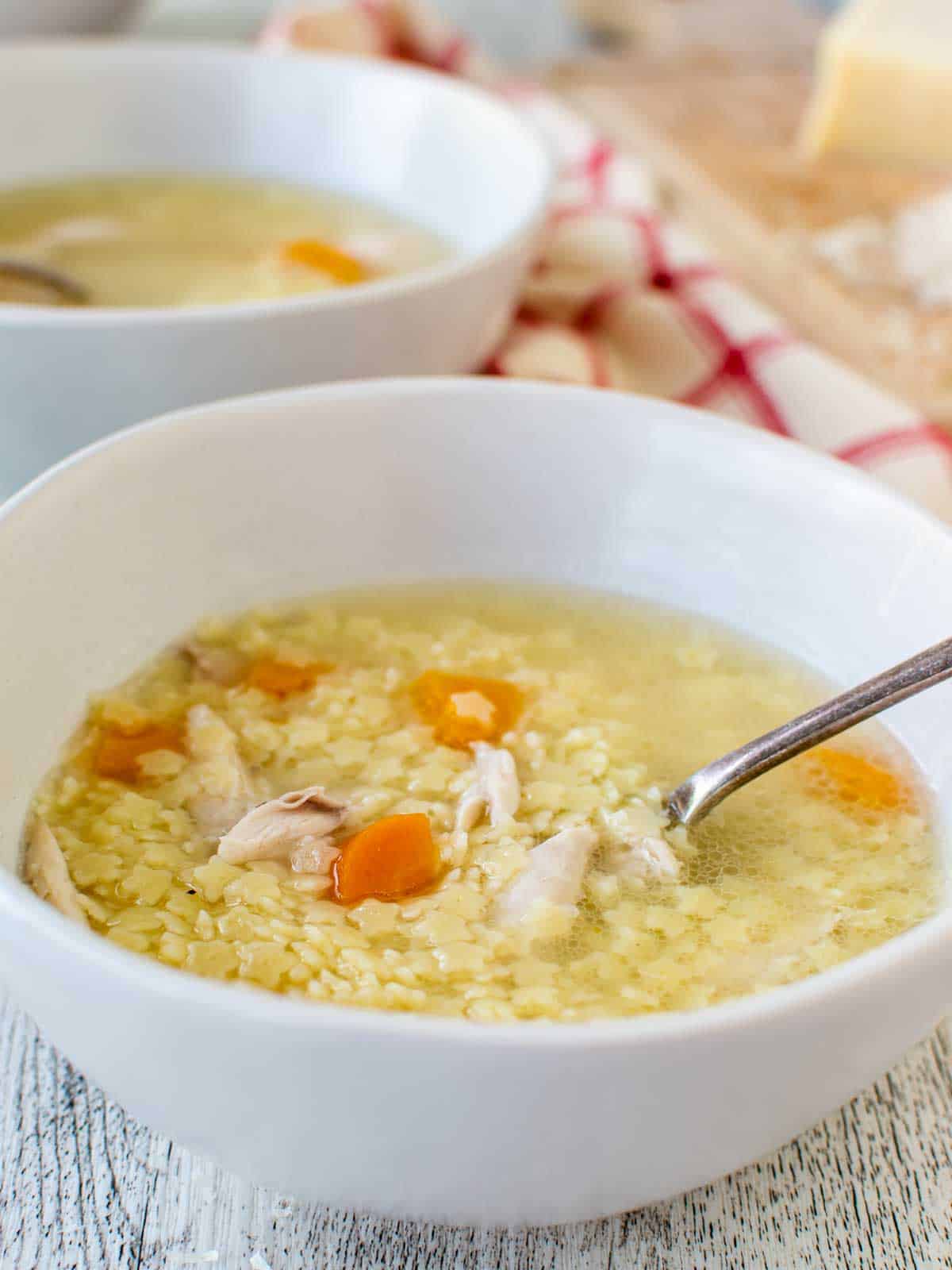 Chicken Pastina Soup in a white bowl with second bowl in the background.