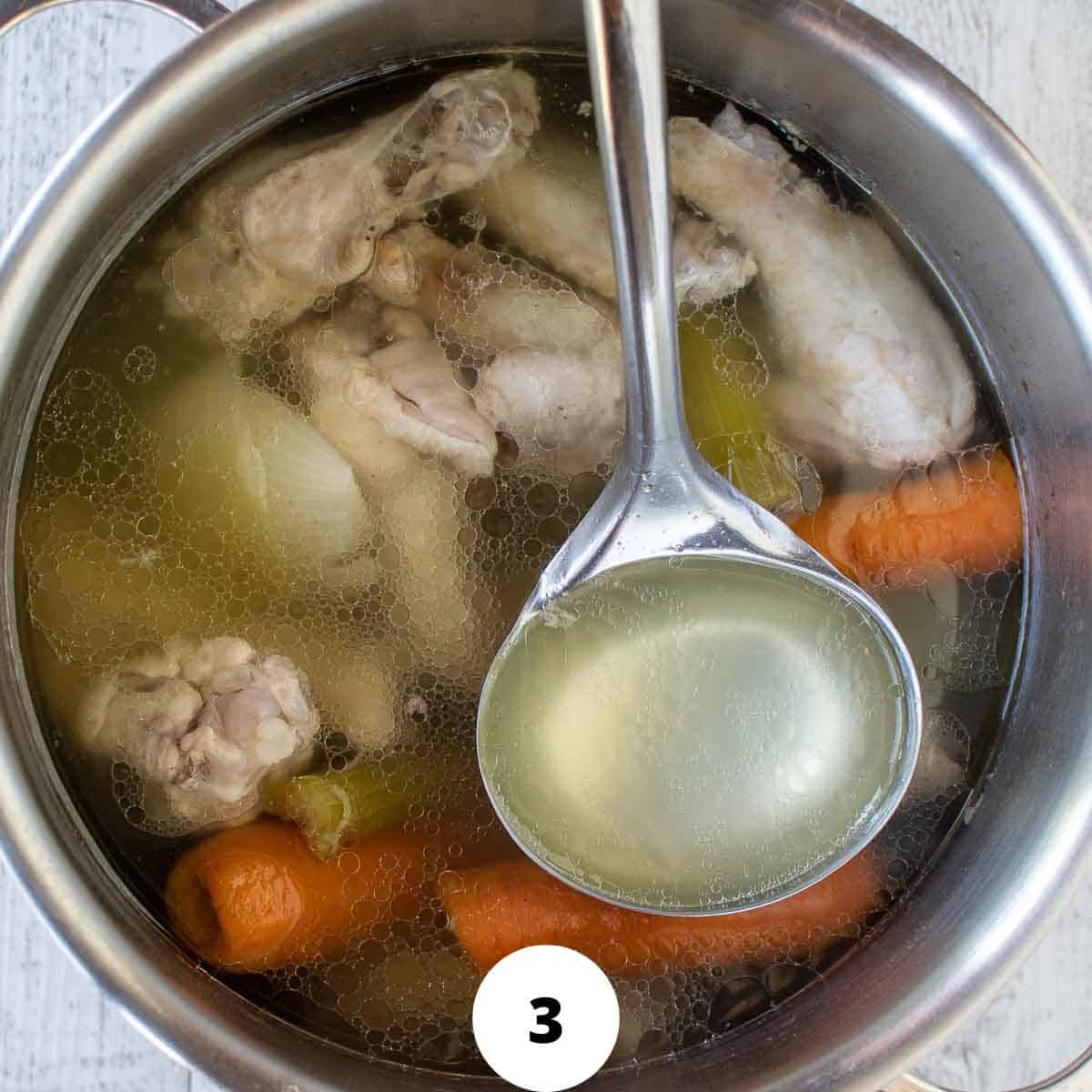 Ladling chicken broth from the pot.