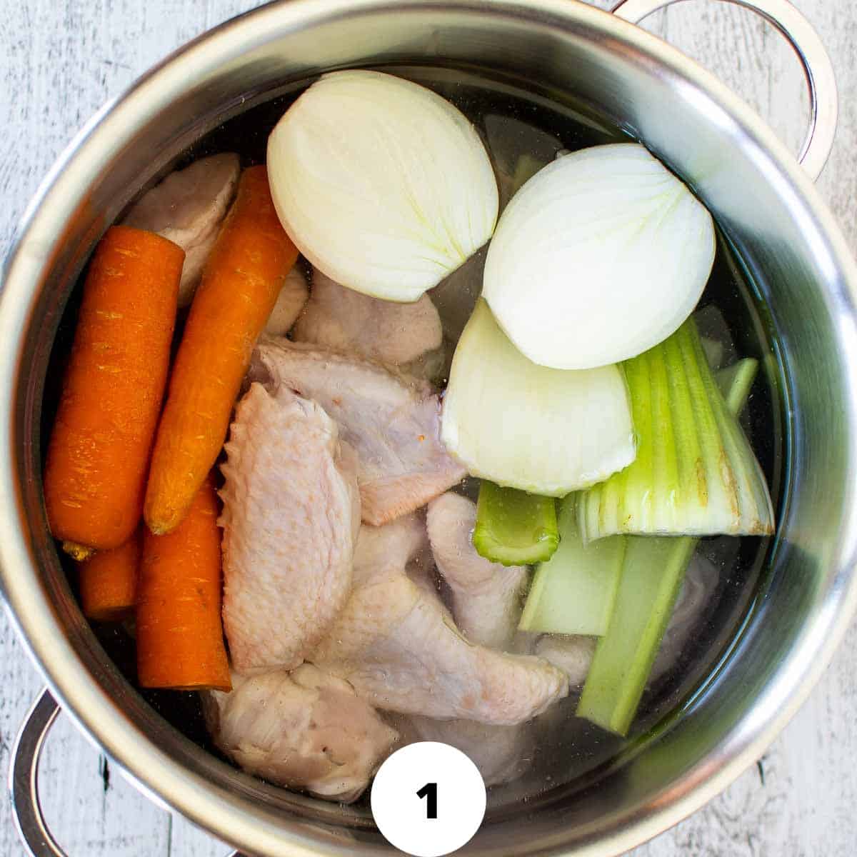 Chicken, carrot, celery and onion in a pot and covered with water.