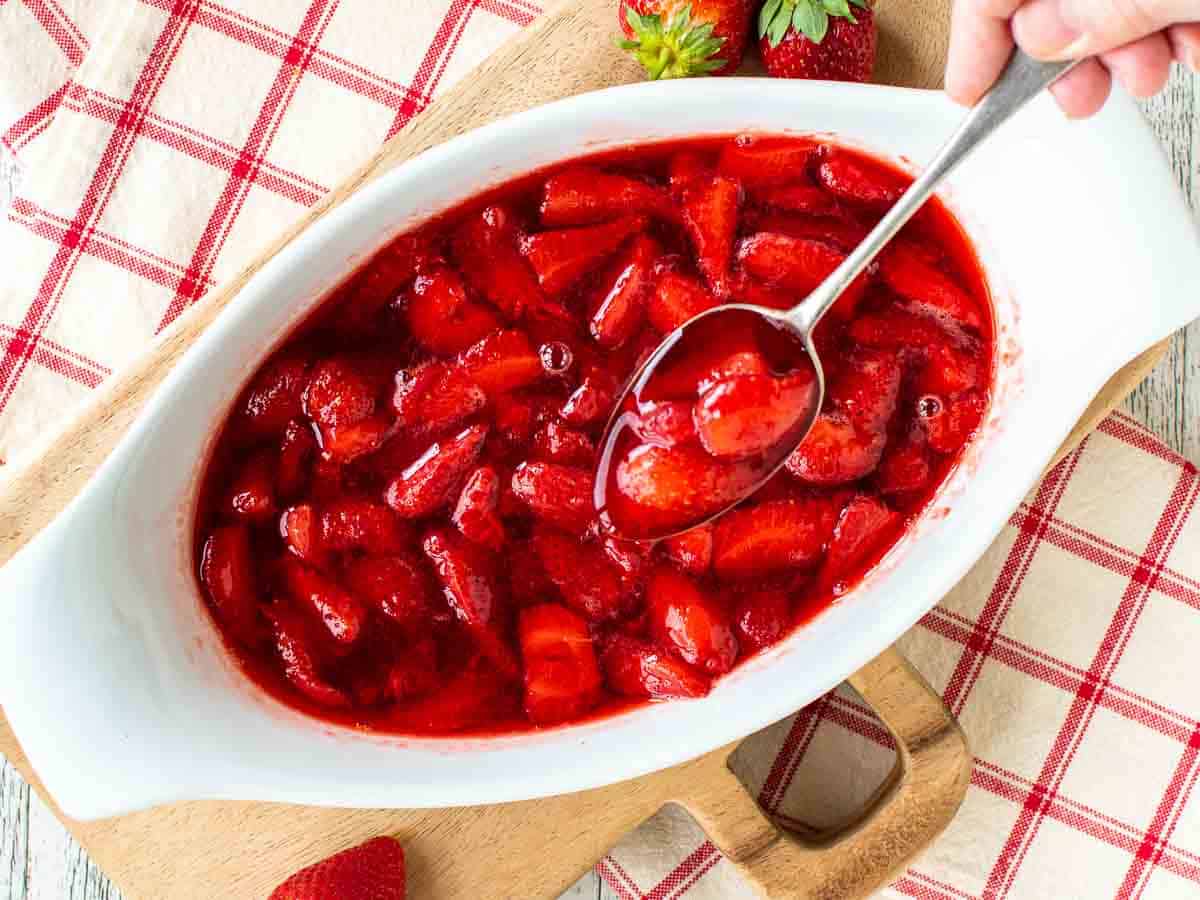 Cooked strawberries in a white oval dish viewed from above.