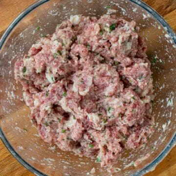 Raw meatballs mixture in a glass bowl viewed from above.