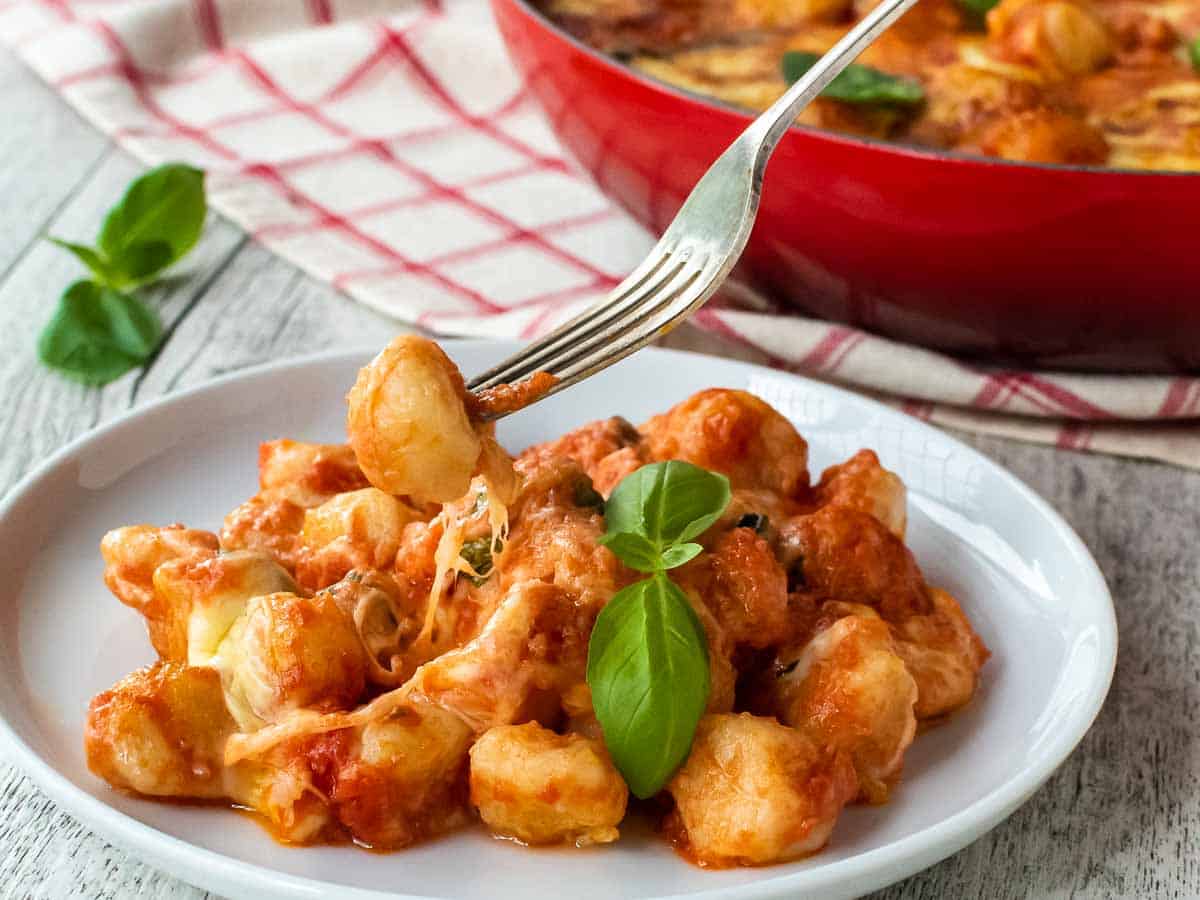 Closeup of gnocchi on a white plate with a fork picking up gnocchi.