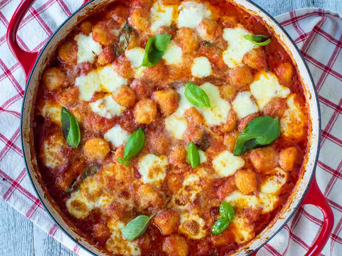 Overhead view of browned, gnocchi sorrentina with garnish of basil leaves.