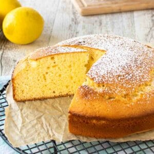 Yellow cake dusted with powdered sugar with a few slices cut viewed from above.