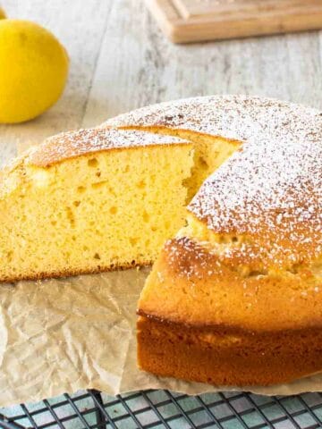 Yellow cake dusted with powdered sugar with a few slices cut viewed from above.