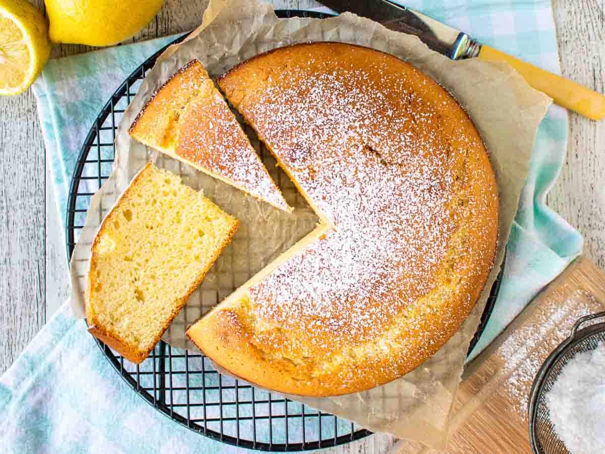 Yellow cake dusted with powdered sugar with a few slices cut viewed from above.