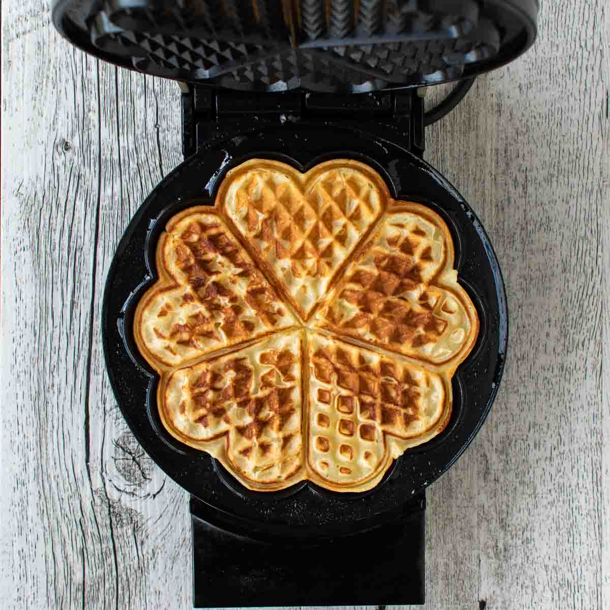 Opened waffle iron revealed browned waffle viewed from above.