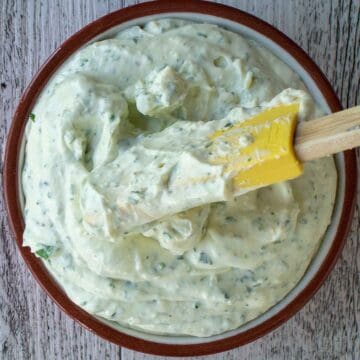 Creamy dip with green flecks in a bowl viewed from above.