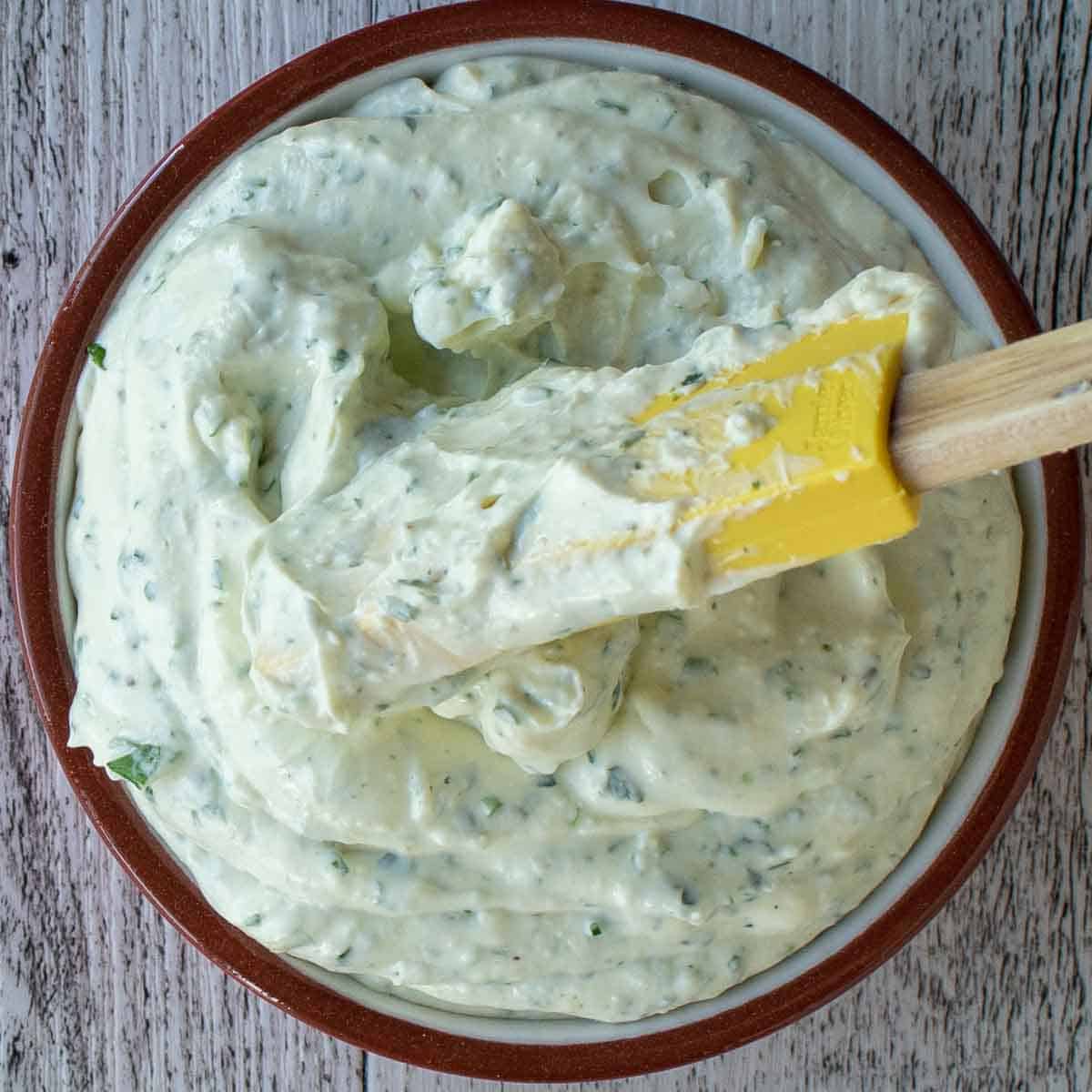 Creamy dip with green flecks in a bowl viewed from above.