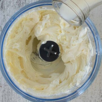 Milk being poured into food processor containing cream cheese.