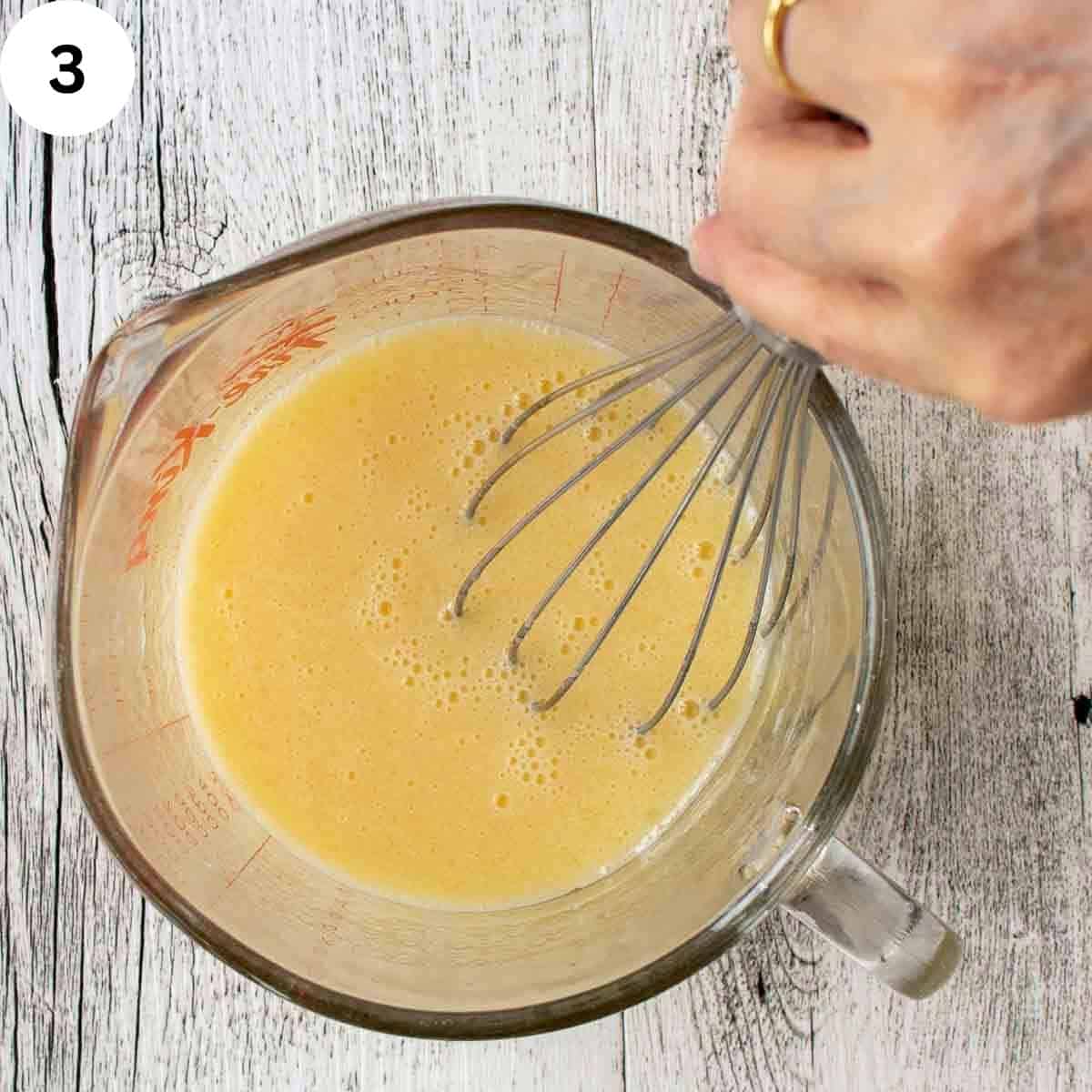 Whisking wet ingredients for muffins with a whisk.