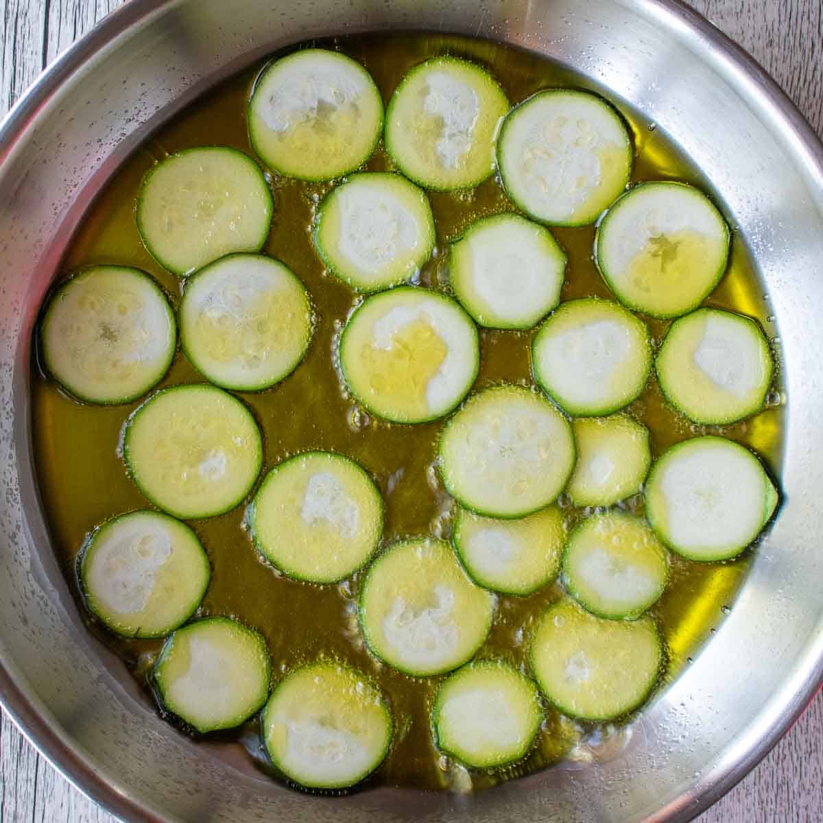 Thin rounds of zucchini frying in oil.