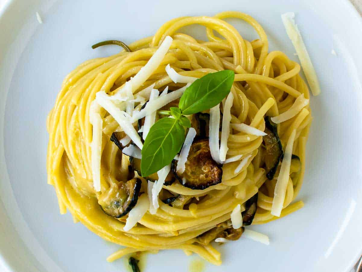 Overhead view of spaghetti piled onto a plate with fried zucchini and cheese viewed from above.