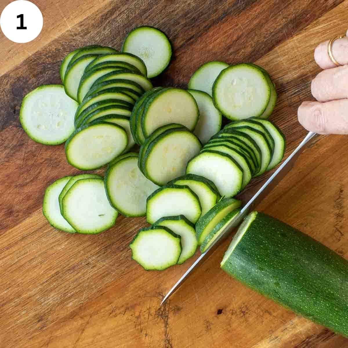 Zucchini being sliced very thinly with a knife.