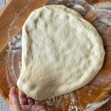 Pizza dough being stretch by hand.