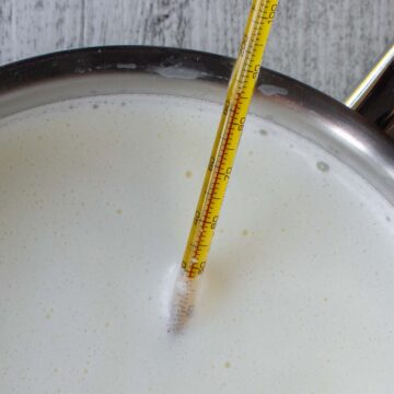 Close up of milk in saucepan with a thermometer in the milk.