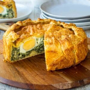 Pie with slice cut out showing a hard boiled egg in a spinach filling.