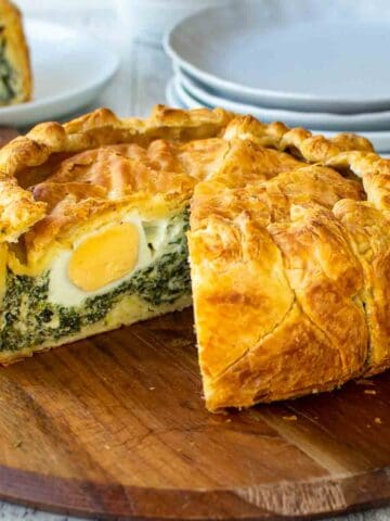 Pie with slice cut out showing a hard boiled egg in a spinach filling.