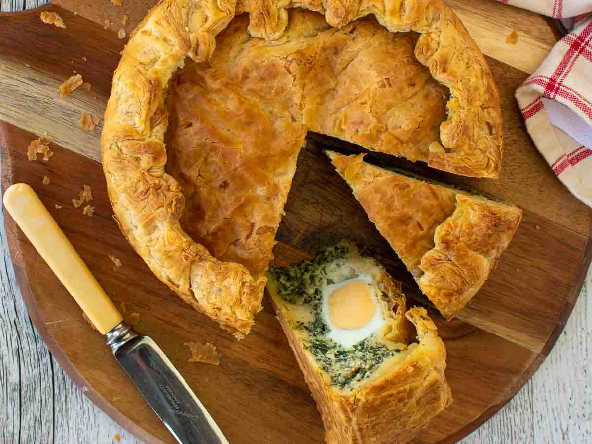 Pie with a two slices cut out showing hard boiled eggs nestled in spinach filling viewed from above.