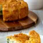 A slice of torta pasqualina on a white plate showing a hard boiled egg in spinach filling.