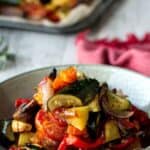 Plate of Italian Roasted Vegetables piled high with a spoon inserted and a red napkin in the background.