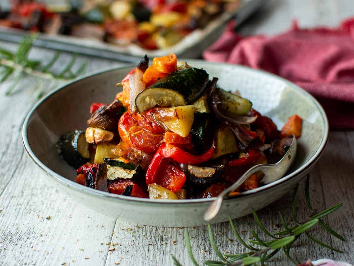 Assorted chopped and roasted Mediterranean vegetables in a pale green bowl.