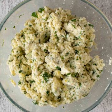 Lumpy ricotta cheese mixture with flecks of green through it.