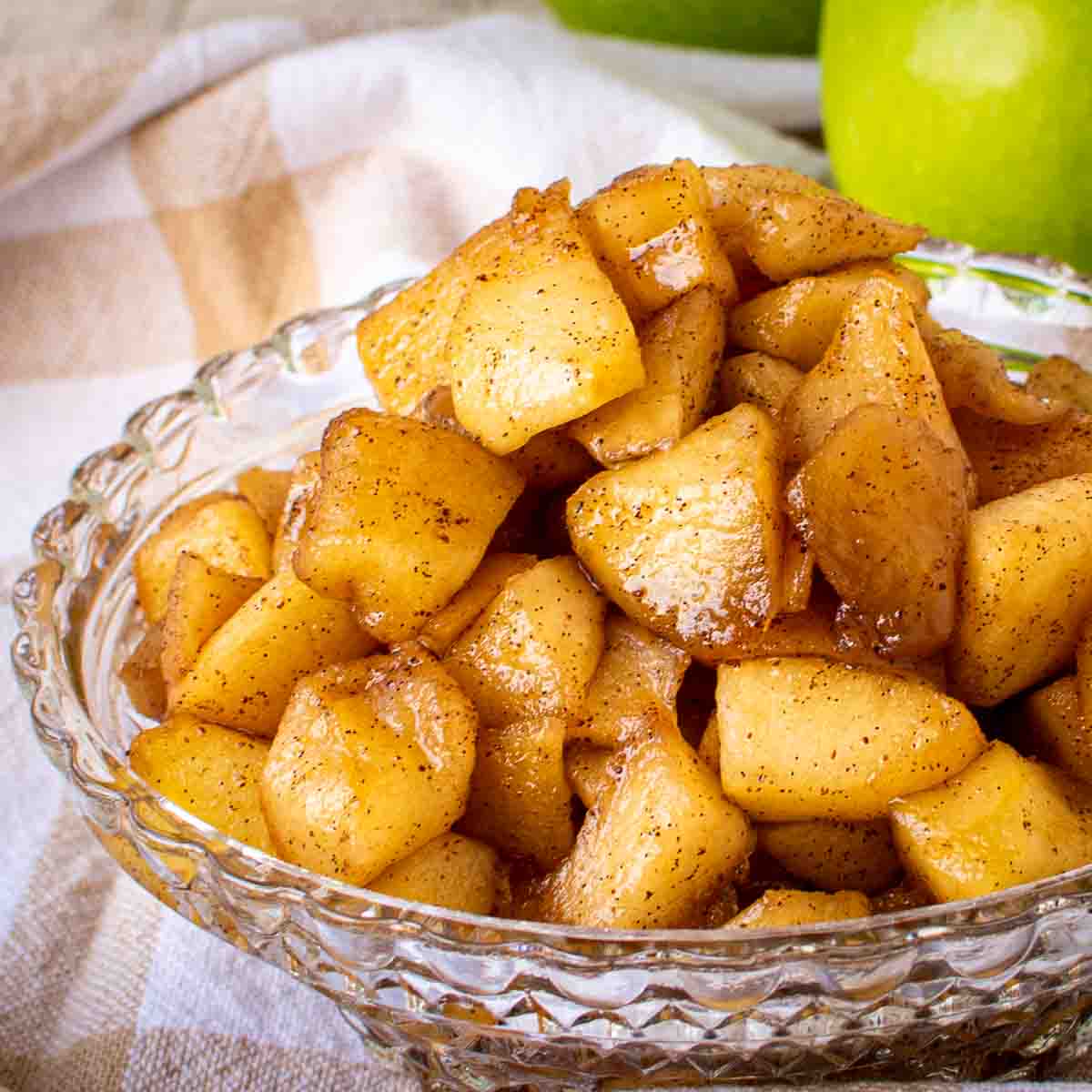 Apple compote in a cut glass dish with green apples in the background.