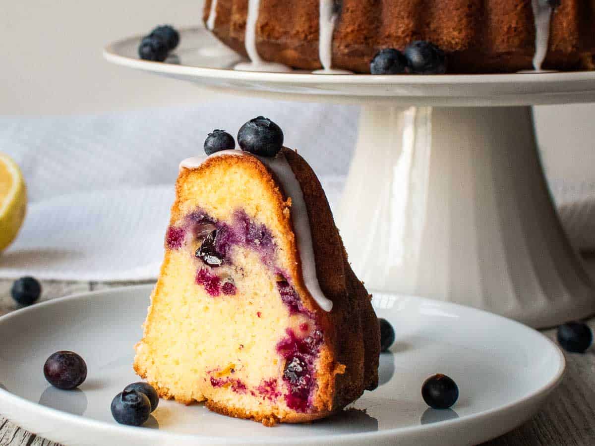 Slice of lemon pound cake with blueberries on a white plate.