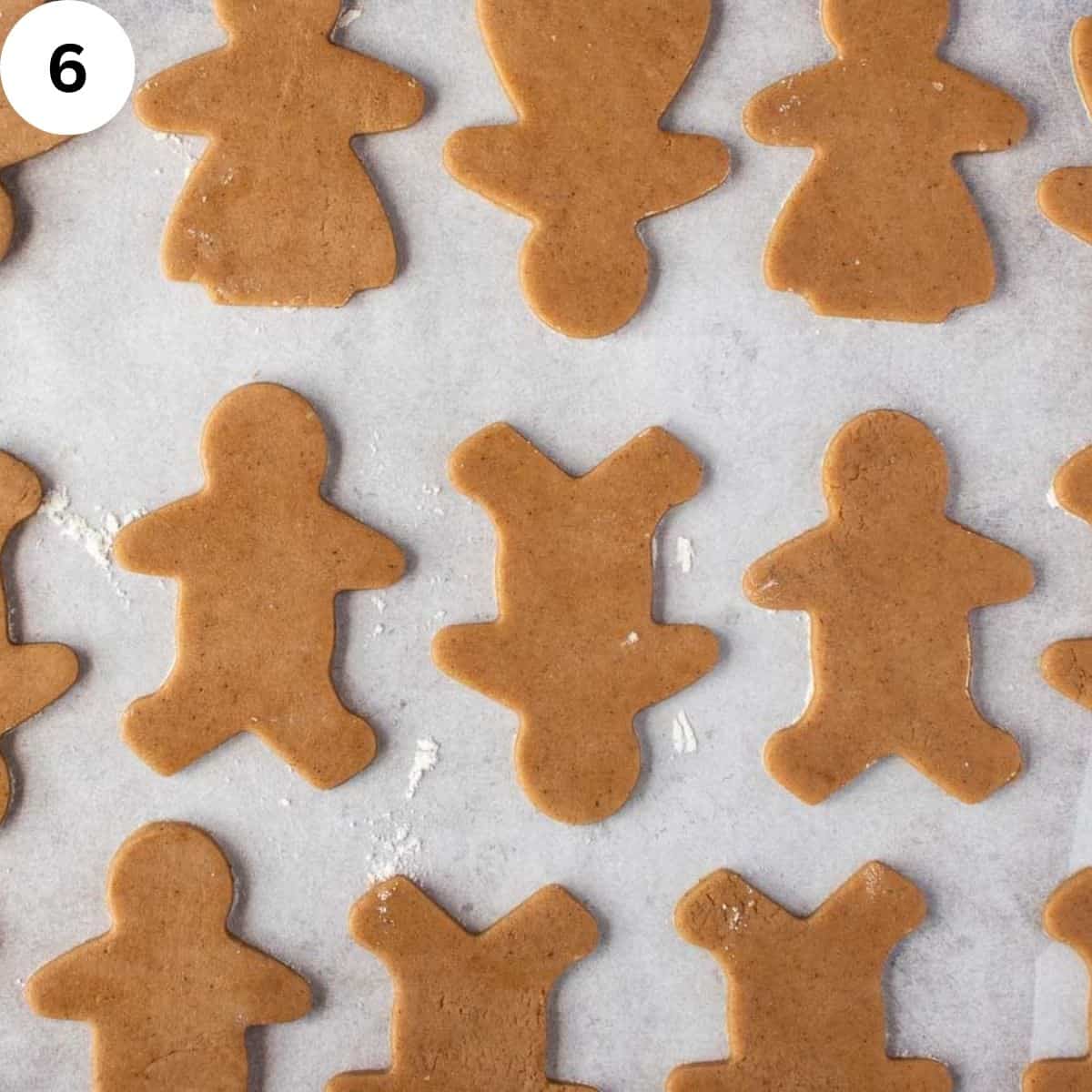 Unbaked gingerbread people on parchment paper.