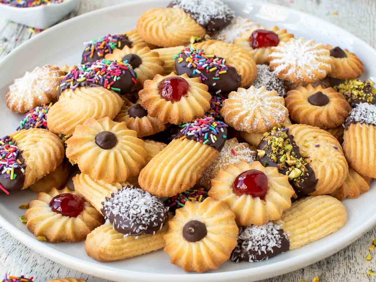 Close up of decorated piped cookies on a white plate.