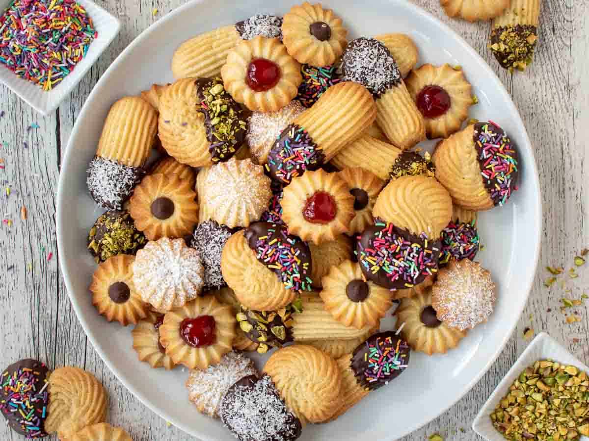 Various shapes of piped cookies with various toppings.