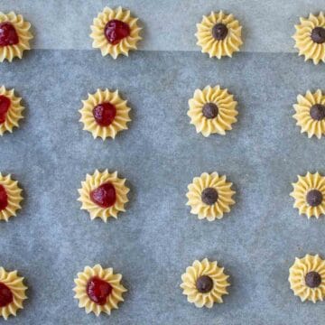 Circular piped cookies topped with candied cherries and choc chips.